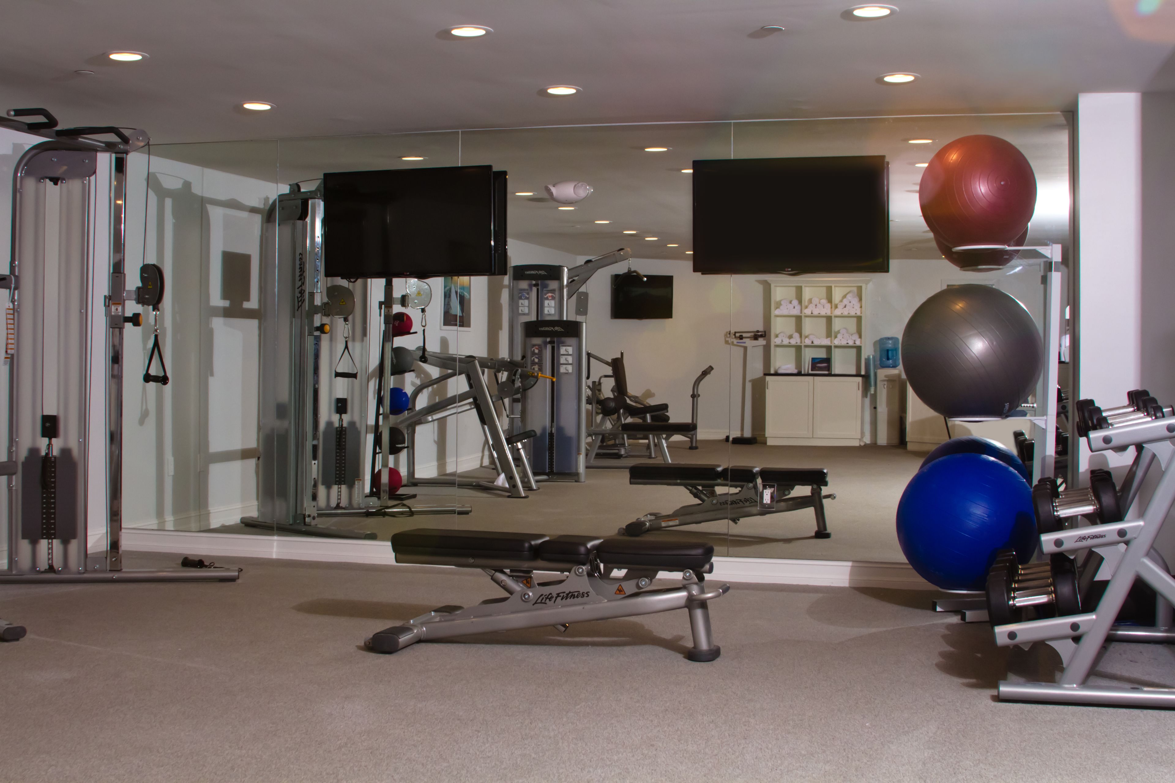 A gym with exercise equipment, a bench, and a mirror.