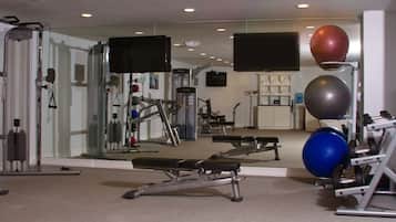 A gym with exercise equipment, a bench, and a mirror.