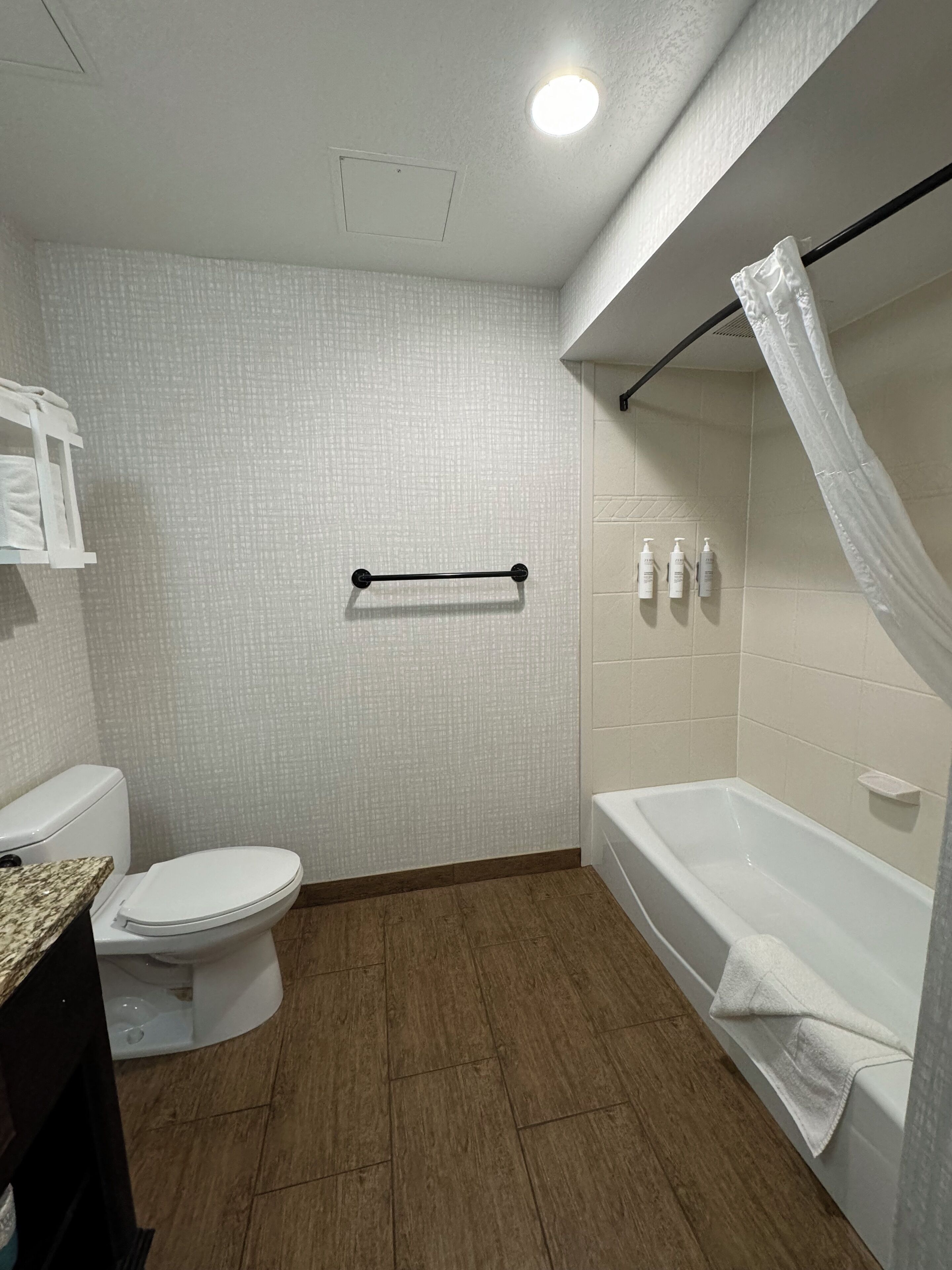 A bathroom with a toilet, a bathtub, and a shower curtain.