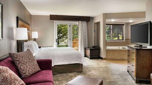 Una habitación de hotel con cama, sofá, televisión, cómoda y maleta.