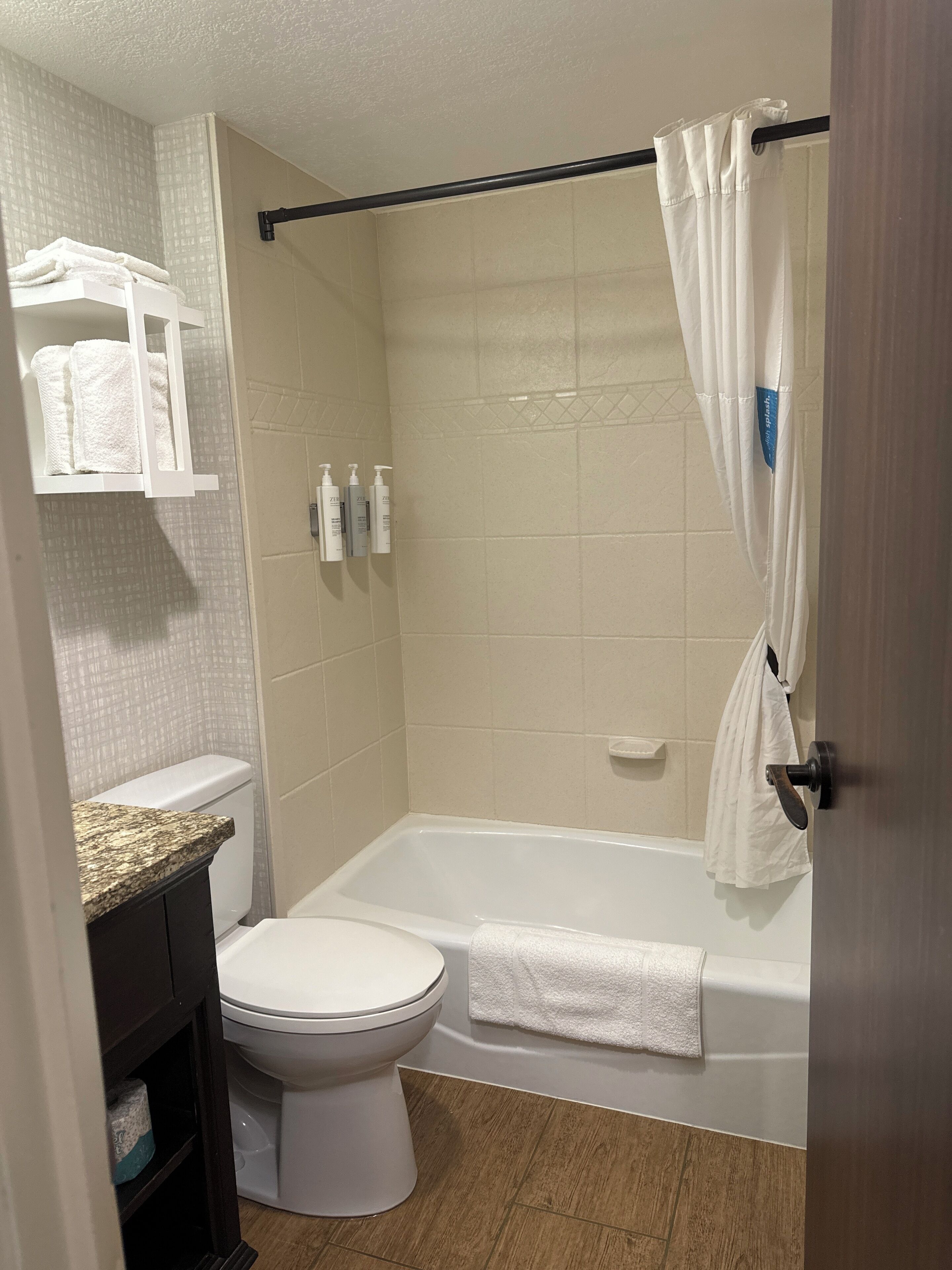 A bathroom with a toilet, bathtub, and shower curtain.