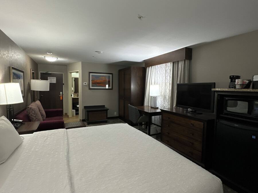 Habitación de hotel con una cama grande, un escritorio, un televisor y un microondas.