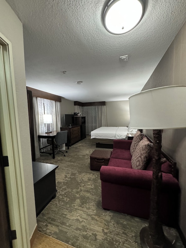 A hotel room with a bed, a desk, a chair, a sofa, a lamp, and a small table. - Hampton Inn Jackson Hole (Jackson)