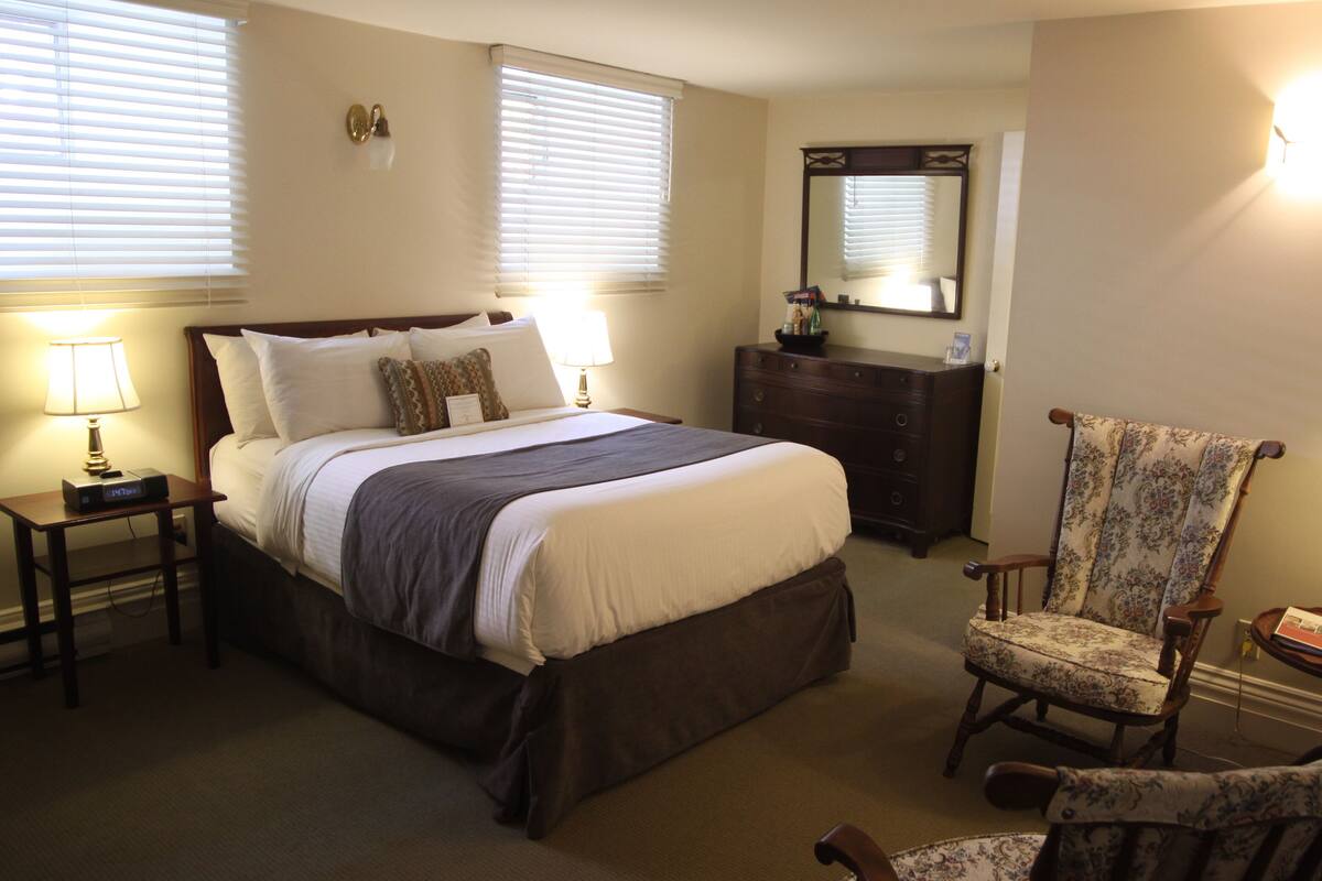 A bedroom with a bed, a dresser, a chair, and a mirror.