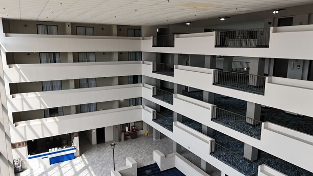 Un hôtel à plusieurs niveaux, avec un atrium central, de nombreux balcons et un comptoir d’accueil.