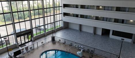 Piscina interior em vários níveis, com vista para o estacionamento através de grandes janelas.