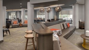 A modern lobby with a curved reception desk, seating areas, and large windows providing natural light. - SpringHill Suites by Marriott Boise ParkCenter (Boise)