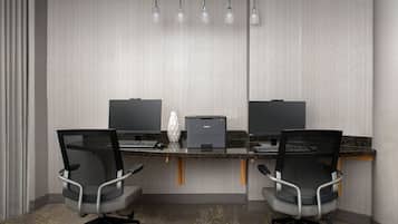 Un espace de bureau moderne comprenant deux bureaux, deux chaises de bureau, une imprimante et un écran d’ordinateur sur chaque bureau.