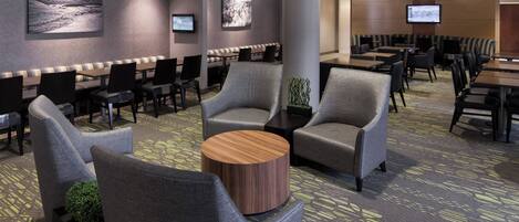A hotel lobby with seating areas, a large pillar, and a television screen.