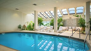 An indoor swimming pool with clear blue water, surrounded by lounge chairs and potted plants. - Embassy Suites by Hilton Richmond (Richmond)