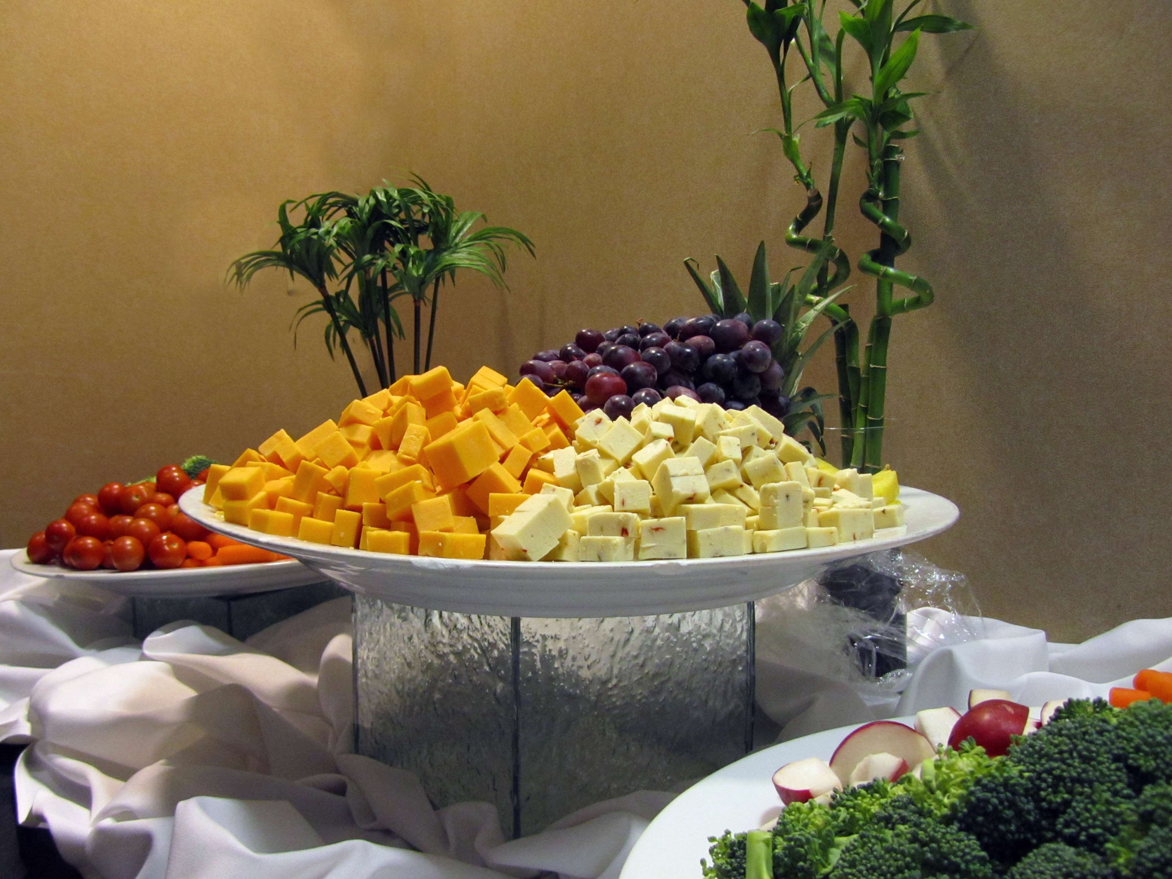 A buffet table with various food items including cheese, grapes, and vegetables.