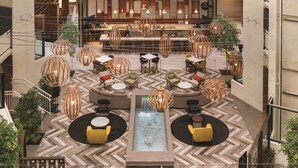 A spacious lobby with a central water feature, multiple seating areas, and a bar in the background. - Embassy Suites by Hilton Richmond (Richmond)
