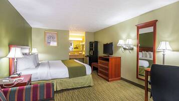 A hotel room with a bed, a desk, a chair, a TV, and a mirror.