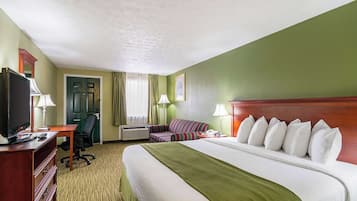 Una habitación de hotel con una cama grande, un escritorio con ordenador, una silla y un televisor.