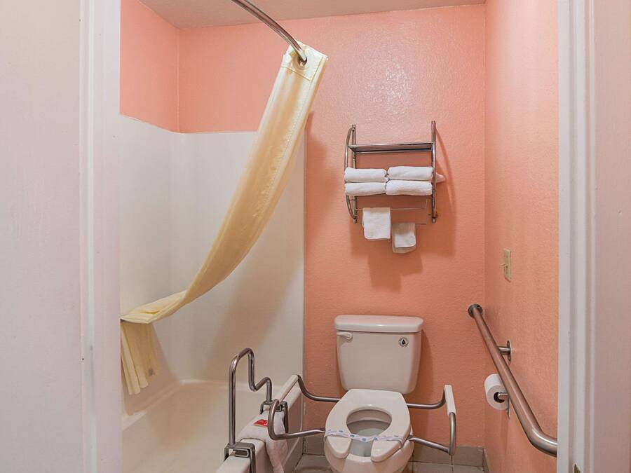 A bathroom with a shower curtain, a toilet, and a towel rack.