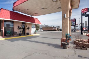 Una estación de servicio con techo rojo, un letrero de ConocoLodge y un pequeño edificio con plantas en macetas y un banco afuera.