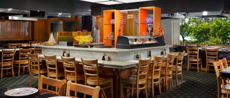 A restaurant with a central bar, wooden chairs, and tables set for dining.