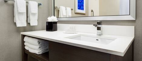 A modern bathroom with a white sink, dark wood vanity, and a large mirror.