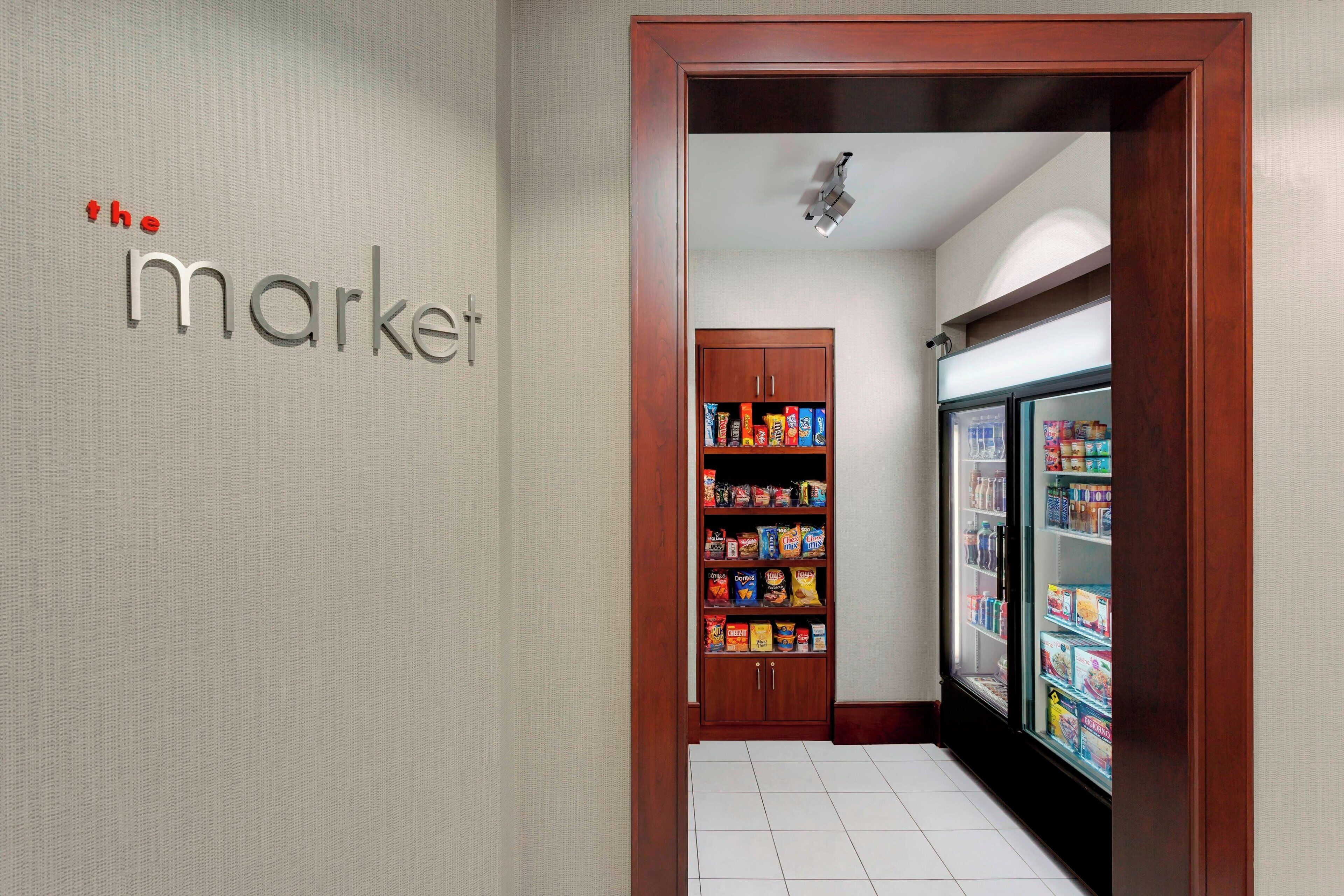 A hallway with a 'market' sign, a wooden cabinet with snacks, and a refrigerated display.