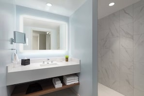 Un baño moderno con tocador blanco, un espejo grande y baldosas de mármol.