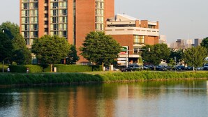 A high-rise building with multiple floors, a parking lot, and a body of water in the foreground.