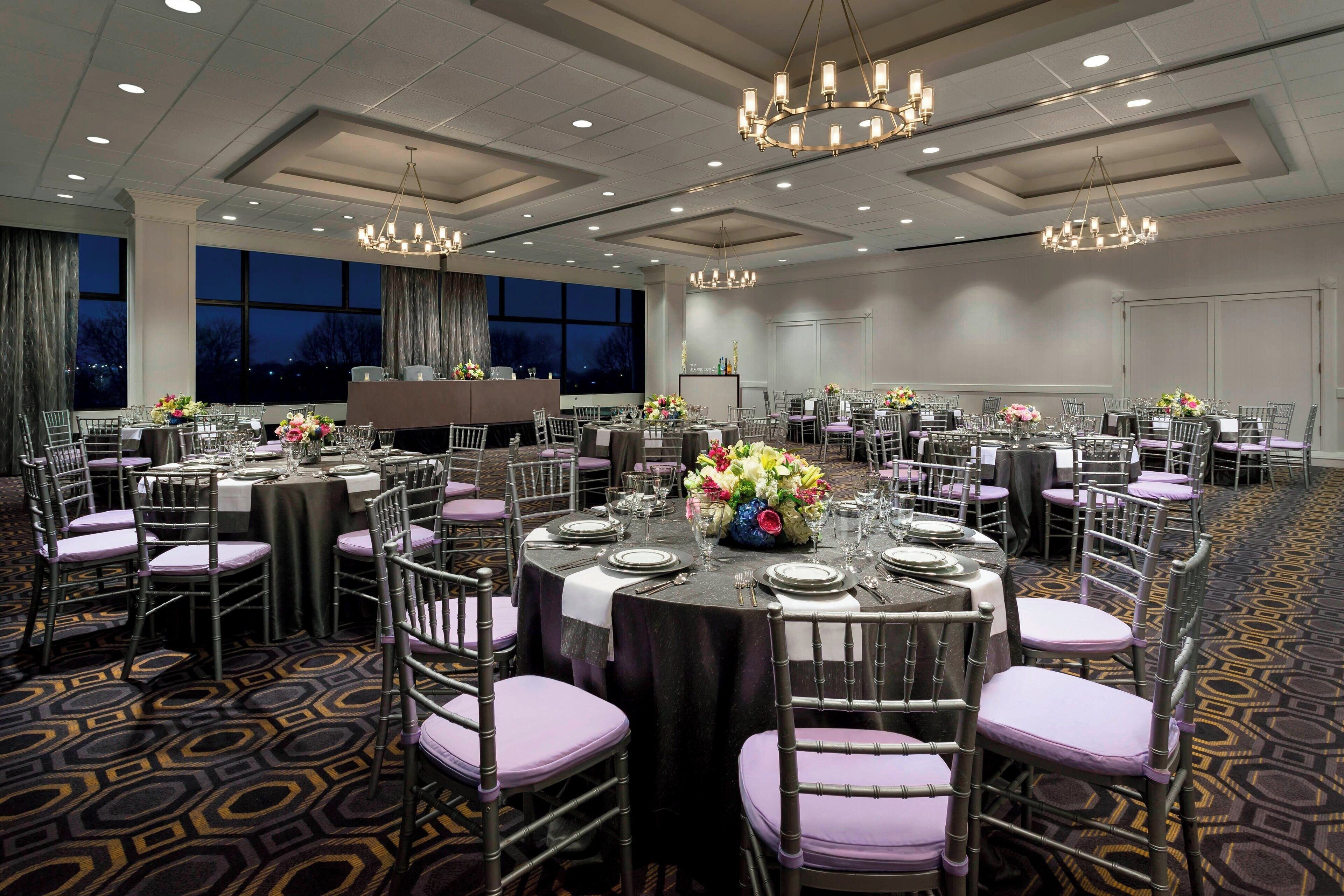 Un amplio salón de banquetes con mesas redondas, sillas y candelabros.
