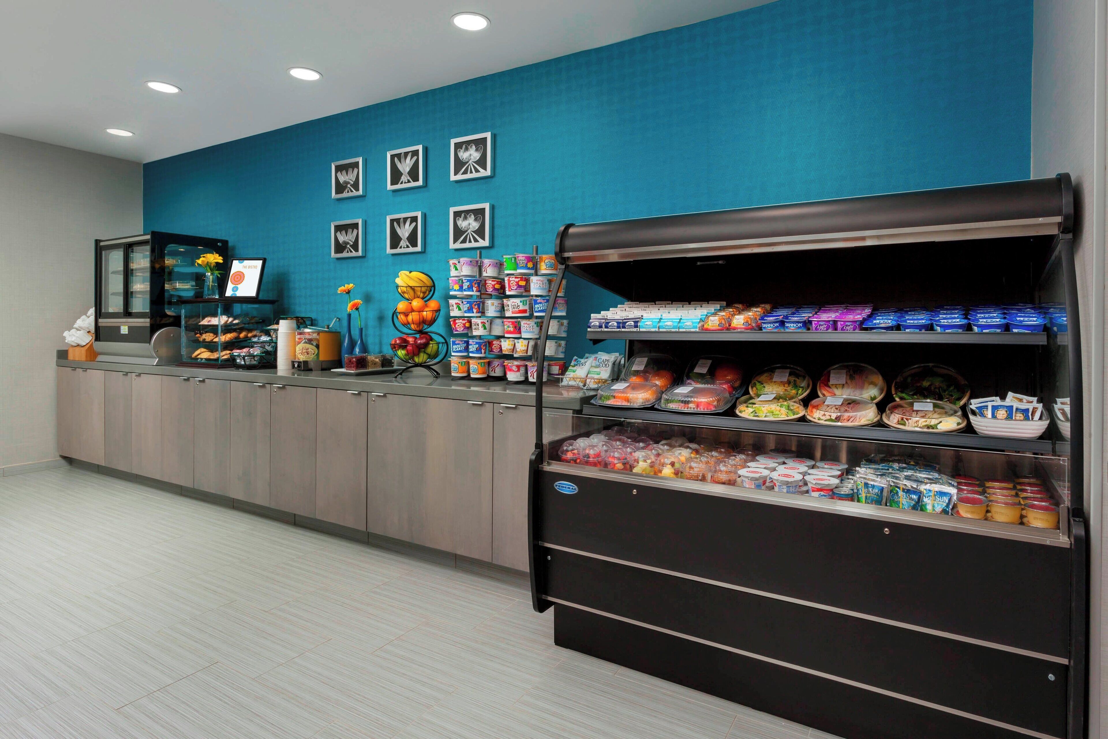 A food service area with a counter, refrigerated display, and various food items.