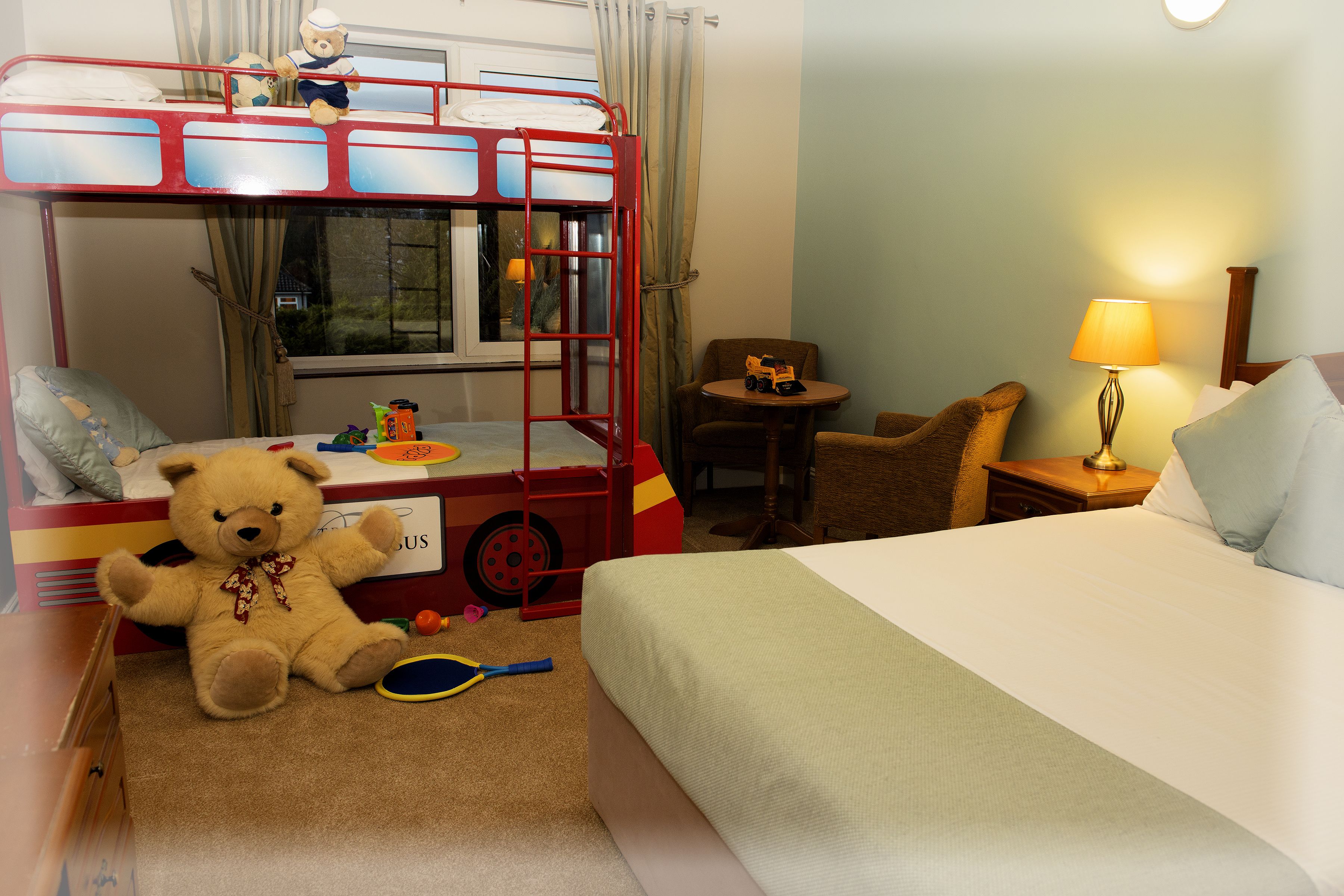 A bunk bed with a toy train, a teddy bear, and a small table with toys.