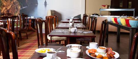 A dining area with tables set for breakfast, including croissants, eggs, and coffee.