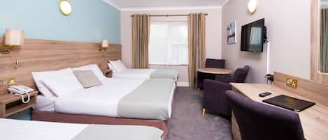 A hotel room with two beds, a desk, a chair, a TV, and a window with curtains.