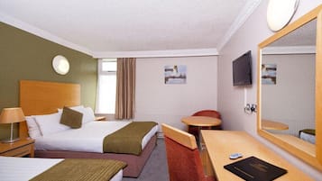 A hotel room with two beds, a desk, a chair, a TV, and a large mirror.