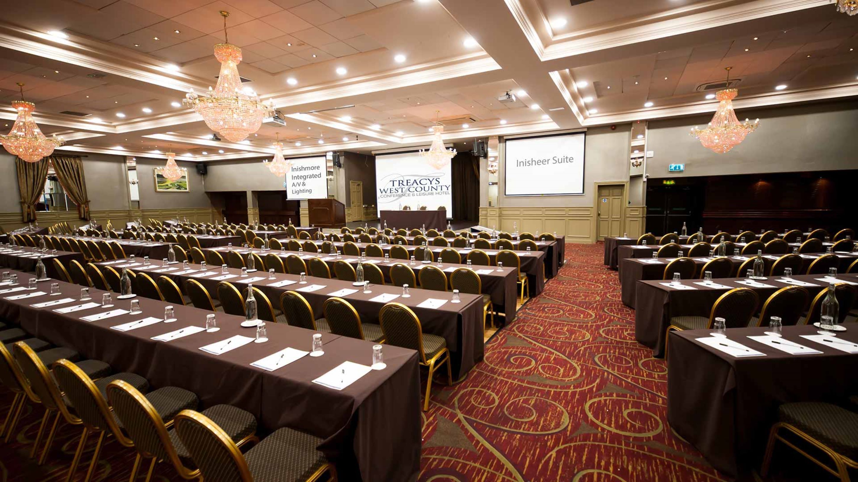 A conference room with rows of tables and chairs, equipped with nameplates and water bottles.