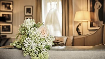 A bouquet of flowers on a grey sofa in a room with a framed picture and a lamp.