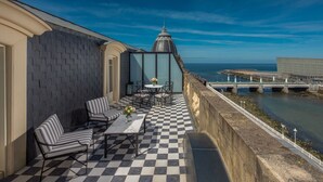 A balcony with checkered flooring, striped chairs, and a table with a vase of flowers. - Hotel Maria Cristina, a Luxury Collection Hotel (San Sebastián)