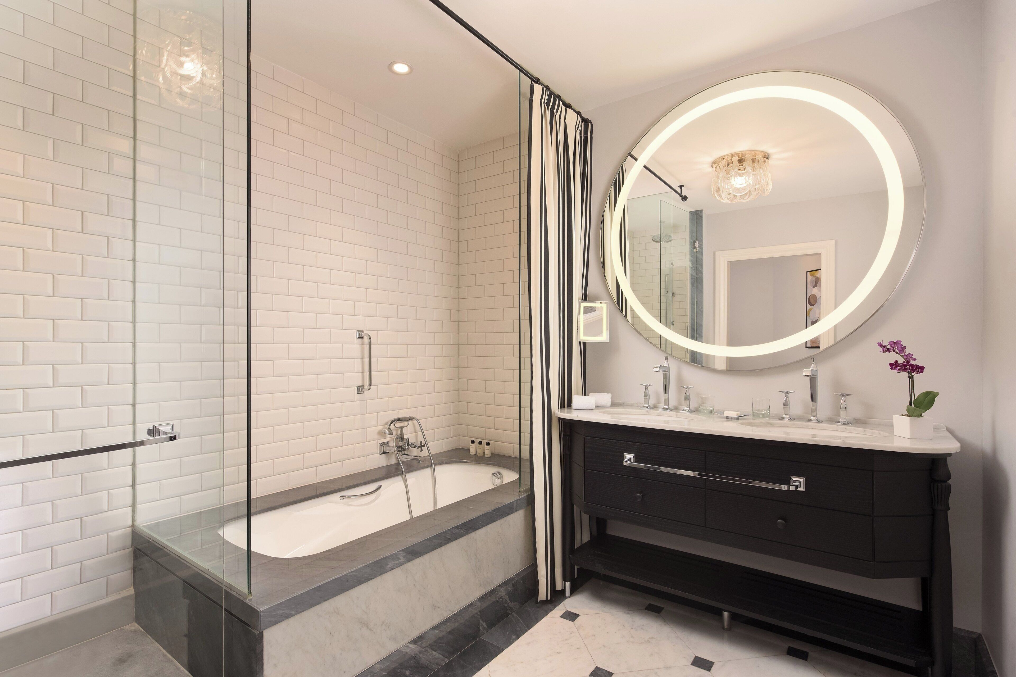 A modern bathroom with a glass-enclosed shower, a freestanding bathtub, and a vanity with a mirror.