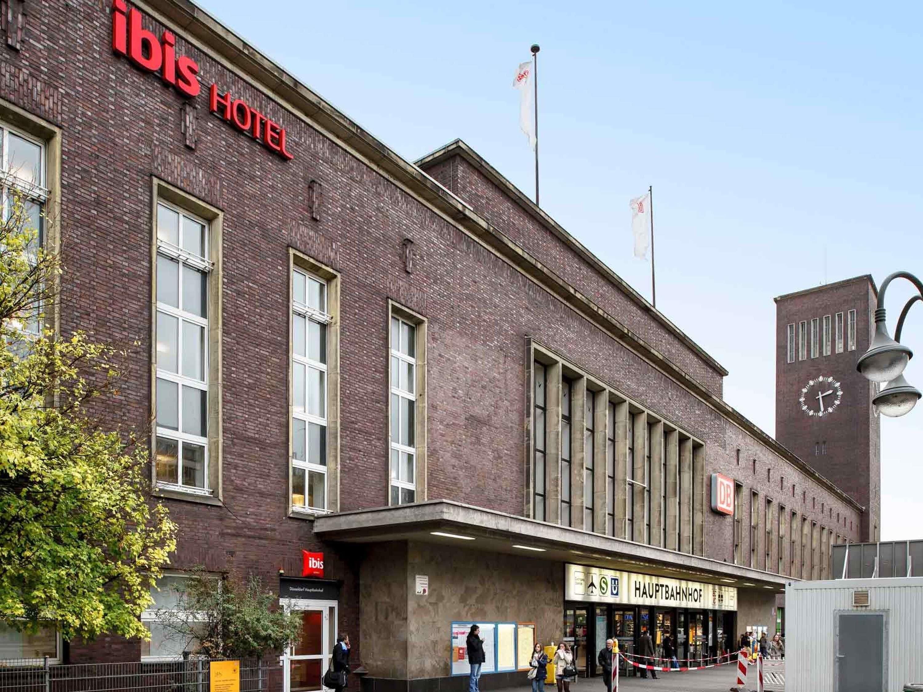 Un edificio de ladrillo con la señalización 'ibis Hotel', una torre del reloj y la entrada a la estación central (Hauptbahnhof).