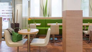 Een modern restaurantinterieur met groene bankjes, witte stoelen en ronde tafels.