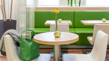 A green sofa, white chairs, and a round table with a vase of flowers.