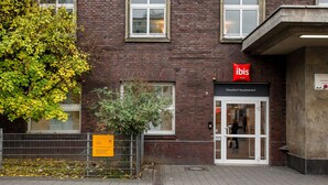 Een gebouw van baksteen met het bord ‘ibis HOTEL’ boven de ingang.