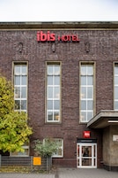 Un edificio in mattoni con il cartello 'ibis HOTEL' sopra l'ingresso.