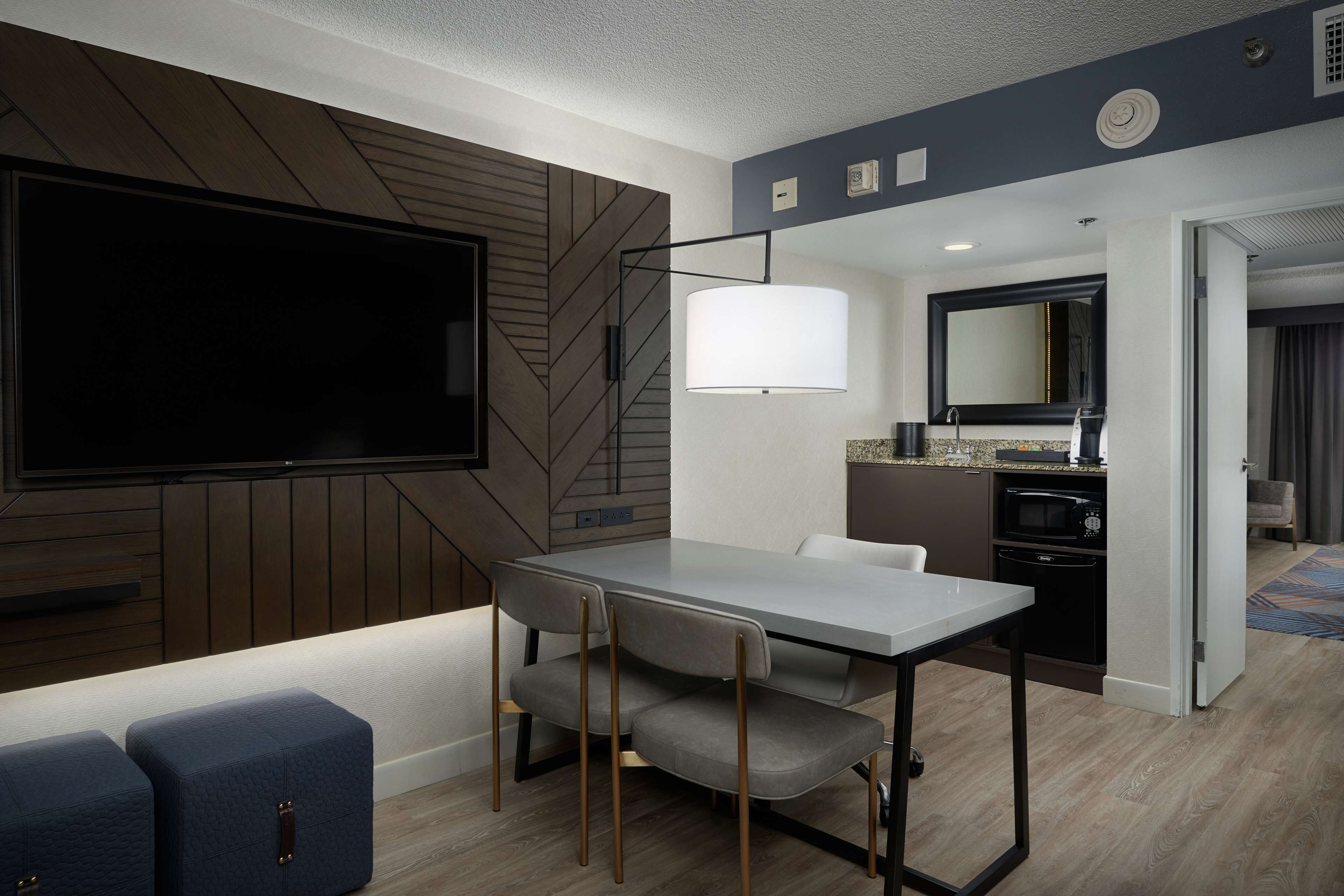 A modern living room with a flat-screen TV, a dining table with chairs, and a sofa.