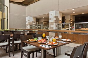 A breakfast area with tables, chairs, and a buffet counter. - Embassy Suites by Hilton Los Angeles Downey (Downey)