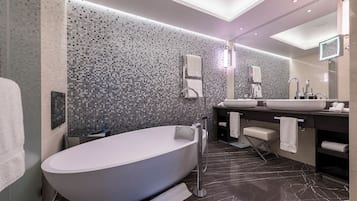 Ein modernes Badezimmer mit freistehender Badewanne, einem großen Spiegel und einem Waschtisch mit Waschbecken und Handtuchhalter.