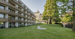 A modern hotel with a courtyard, a large tree, and a historic building in the background. - Royal Savoy Hotel & Spa (Lausanne)