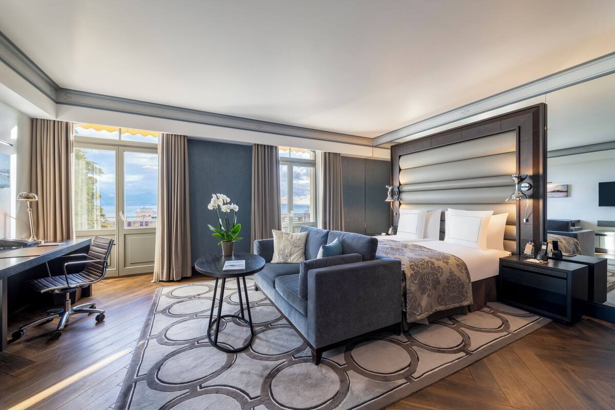 Habitación de hotel moderna con una cama grande, un escritorio, un sofá y vistas a la ciudad.