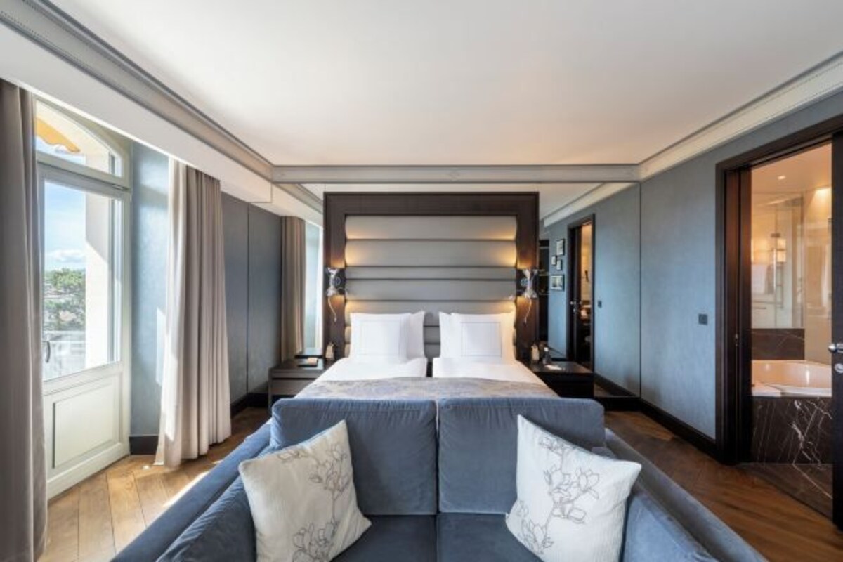 Una habitación de hotel moderna con una cama grande, un sofá, un baño y vistas al exterior.