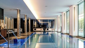 Ein moderner, überdachter Schwimmbereich mit Glasboden, Sitzgelegenheit und großen Fenstern.