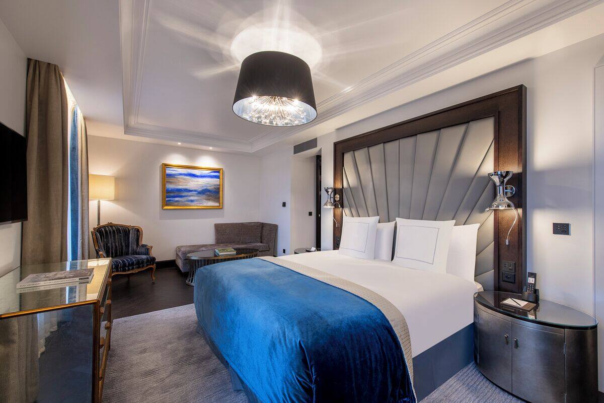 Una habitación de hotel moderna con una cama grande, un escritorio, una silla y un televisor.