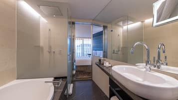 A modern bathroom with a large bathtub, two sinks, and a shower.