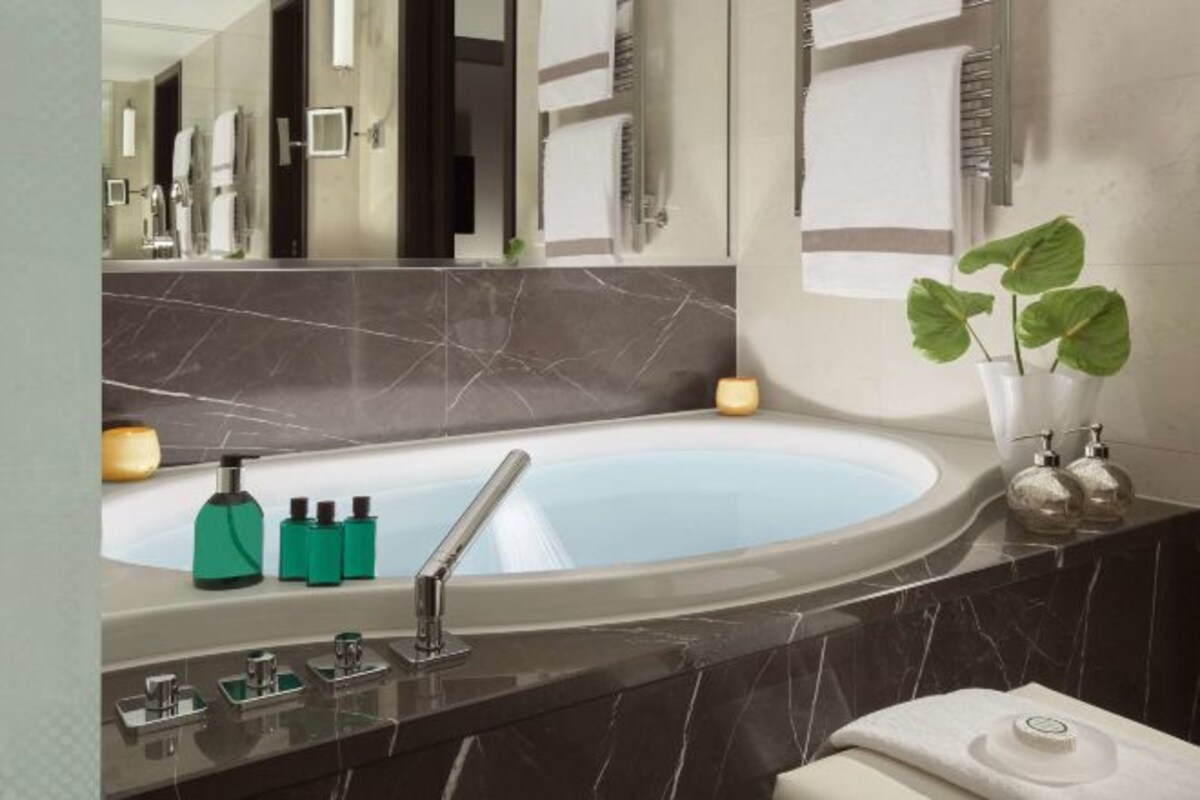Un baño moderno con una bañera grande, un espejo y una planta.